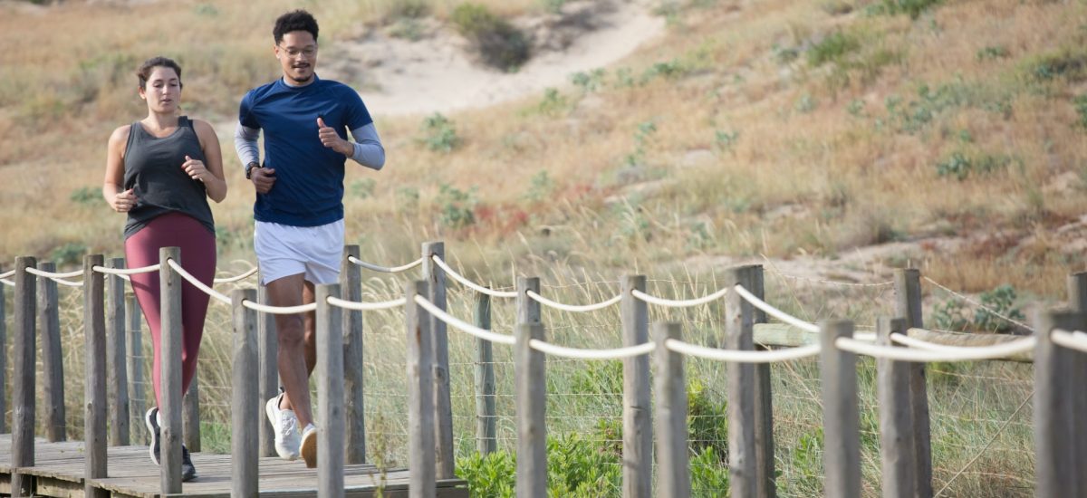 two people jogging on a boardwalk